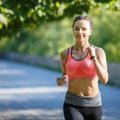 Beautiful young woman in pink top jogging in park Royalty Free Stock Photo