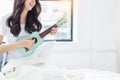 Beautiful young woman play little guitar or ukulele guitar at home Asian young girl love playing ukulele and sing a song with Royalty Free Stock Photo