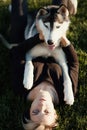 Beautiful young woman playing with funny husky dog outdoors in park at sunny day