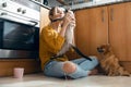 Beautiful young woman playing with her cute lovely animals sitting on the floor in the kitchen at home