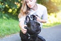 Beautiful young woman playing with her French bulldog in a park outdoors. Close-up portrait of pleased dog with short Royalty Free Stock Photo