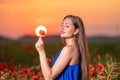 beautiful young woman playing with sun ball while standing in poppy field in warm sunset light Royalty Free Stock Photo