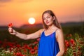 beautiful young woman playing with sun ball while standing in poppy field in warm sunset light Royalty Free Stock Photo