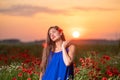 beautiful young woman playing with sun ball while standing in poppy field in warm sunset light Royalty Free Stock Photo