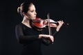 Beautiful young woman playing violin over black Royalty Free Stock Photo