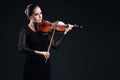 Beautiful young woman playing violin over black Royalty Free Stock Photo