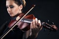 Beautiful young woman playing violin over black Royalty Free Stock Photo