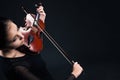 Beautiful young woman playing violin over black Royalty Free Stock Photo