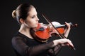 Beautiful young woman playing violin over black Royalty Free Stock Photo