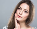 Beautiful young woman portrait cute tender pure smiling touching her cheek by palm attractive gray background Royalty Free Stock Photo