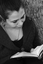 Beautiful young woman portrait reading a book under a tree