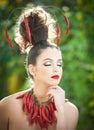 Beautiful young woman portrait with red hot spicy peppers around the neck and in hair, fashion model with creative food vegetable