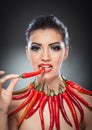 Beautiful young woman portrait with red hot and spicy peppers, fashion model with creative food vegetable make up Royalty Free Stock Photo