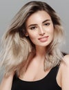 Beautiful young woman portrait smiling posing attractive blond with flying hair on gray background Royalty Free Stock Photo