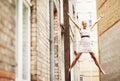 Im flying. A beautiful young woman posing playfully on a fire escape ladder in between buildings. Royalty Free Stock Photo