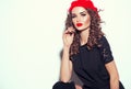 Beautiful young woman posing in studio in black dress and red beret. Beauty model girl portrait. Trendy outfit