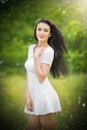 Beautiful young woman posing in a summer meadow. Portrait of attractive brunette girl with long hair relaxing in nature, outdoor