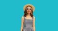 Beautiful young woman posing wearing summer straw hat, striped dress on blue background Royalty Free Stock Photo