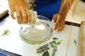 Beautiful young woman pouring polymer plastic mass on mold with an impression of plants