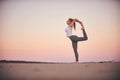 Beautiful young woman practices yoga asana Natarajasana - Lord Of The Dance pose in the desert at sunset Royalty Free Stock Photo