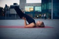 Beautiful young woman practices yoga asana Padma Sarvangasana - shoulderstand lotus pose outdoors against the background of a mode