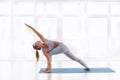 Beautiful young woman practices yoga asana Parivritta Parshvakonasana - Revolving side angle posture at the yoga studio