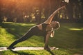 Beautiful young woman practices yoga asana Parivritta Parshvakonasana - Revolving side angle posture in the park