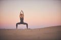 Beautiful young woman practices yoga asana Stupasana in the desert at sunset Royalty Free Stock Photo