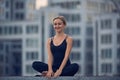 Beautiful young woman practices yoga asana Sukhasana - The Easy Sitting crosslegged Pose outdoors against the background of a mode