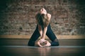 Beautiful young woman practices yoga asana Ushtrasana - Camel pose at the yoga studio on a brick wall background.