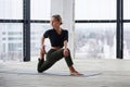 Beautiful young woman practices yoga asana Virabhadrasana 1 - warrior pose 1 at the yoga class Royalty Free Stock Photo