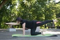 Beautiful young woman practices yoga in the park on the mat. Chubby girl leads a healthy lifestyle