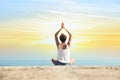 Beautiful young woman practicing yoga near sea at sunrise, back view Royalty Free Stock Photo