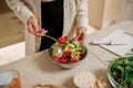 Beautiful young woman preparing vegetable vegan salad in the kitchen. Healthy food and diet concept lifestyle. Cook at home Royalty Free Stock Photo