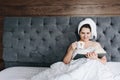 Beautiful young woman reading a book in bed and drinking a cup of coffee with space for text Royalty Free Stock Photo