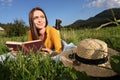 Beautiful young woman reading book on green meadow in mountains Royalty Free Stock Photo