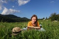 Beautiful young woman reading book on green meadow in mountains Royalty Free Stock Photo