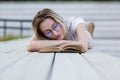 Beautiful young woman reading a book lying on the bench in the park Royalty Free Stock Photo