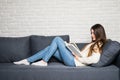 Beautiful young woman reading book and lying on sofa at home Royalty Free Stock Photo