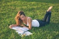 Beautiful young woman reading on a green meadow Royalty Free Stock Photo