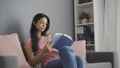 Beautiful young woman reading a sad book while sitting on sofa Royalty Free Stock Photo