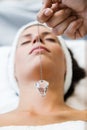 Beautiful young woman receiving gemstone therapy in spa. Royalty Free Stock Photo