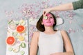 Beautiful young woman receiving spa treatment with pink cosmetic mask, and slices of cucumber on her eyes, skincare Royalty Free Stock Photo