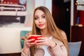 Beautiful young woman with a red cup of coffee at a cafe. Woman drinking hot latte coffee at cozy coffee shop Royalty Free Stock Photo