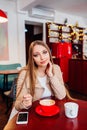 Beautiful young woman with a red cup of coffee at a cafe. Woman drinking hot latte coffee at cozy coffee shop Royalty Free Stock Photo