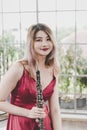 Beautiful young woman in a red dress playing the clarinet .,Classical musician oboe playing Royalty Free Stock Photo