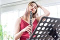 Beautiful young woman in a red dress playing the clarinet .,Classical musician oboe playing Royalty Free Stock Photo