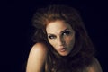 Beautiful young woman with red hair and freckles portrait, beauty shoot on dark background