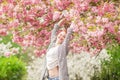 Beautiful young woman with red hair having fun standing in cherry blossom tree