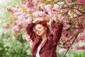 Beautiful young woman with red hair having fun standing in cherry blossom tree Royalty Free Stock Photo
